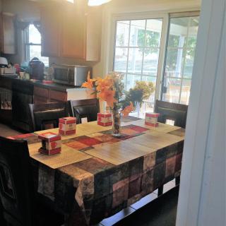 A cozy kitchen with a decorated dining table featuring flowers and a colorful tablecloth.