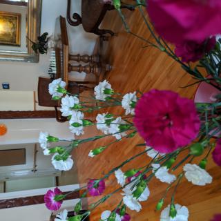 A vase of vibrant flowers decorates an elegantly furnished room with a wooden floor.