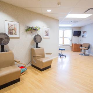 A spacious and modern waiting area in a hair salon, featuring comfortable seating and fans for customer comfort.