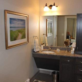 A modern bathroom with a vanity and mirror, featuring a decorative painting on the wall.