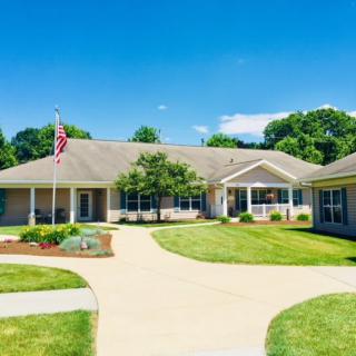 A residential building with a driveway and a well-maintained lawn on a clear day.
