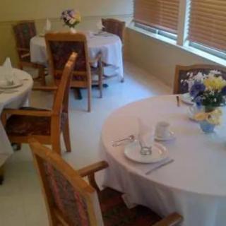 A cozy dining area set with tables, chairs, and floral arrangements.