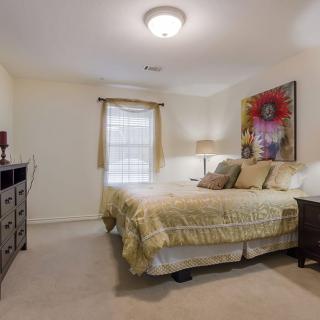 A cozy bedroom featuring a comfortable bed, artwork, and warm lighting.