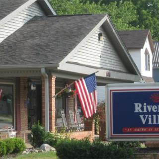 A suburban house with an American flag displayed and a real estate sign in the front yard.