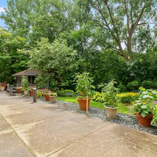 A tranquil garden patio with potted plants and a gazebo surrounded by lush greenery.