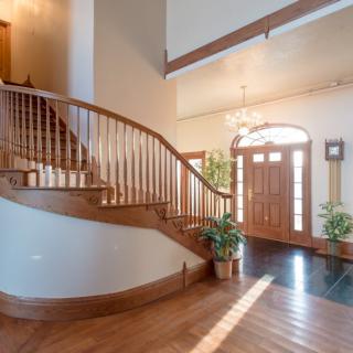 A welcoming foyer with a curved wooden staircase and ample natural light.