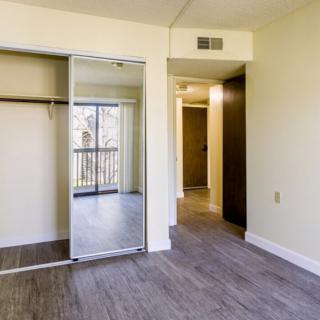 An empty bedroom with a mirrored closet and wood flooring.
