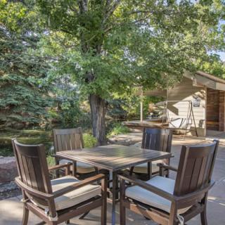 A cozy outdoor patio area with a table and chairs surrounded by trees.