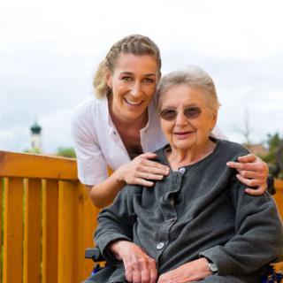 A caregiver shares a warm moment with an elderly woman in a wheelchair, showcasing the bond of companionship.