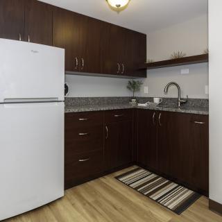 A modern kitchen with dark wood cabinets and a white refrigerator.