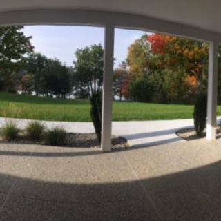 A view from a covered patio overlooking a garden with lush green grass and trees showing autumn colors.