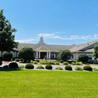 A picturesque view of a residential building with a well-maintained lawn and clear blue sky.