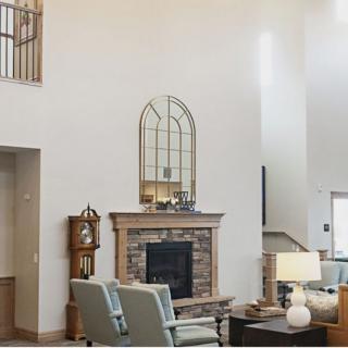 A spacious living room with a high ceiling, featuring a cozy fireplace and elegant furniture.