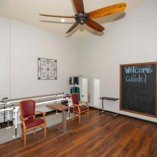 A well-lit physical therapy room with exercise equipment and a chalkboard.