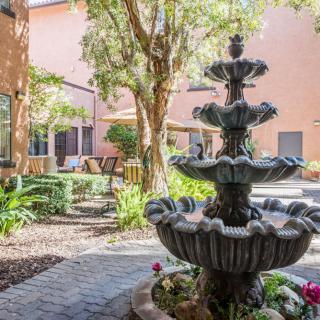 A serene courtyard with a multi-tiered fountain surrounded by trees and a cozy seating area.