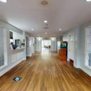 A bright and spacious hallway with wood flooring, featuring a reception desk and a waiting area.