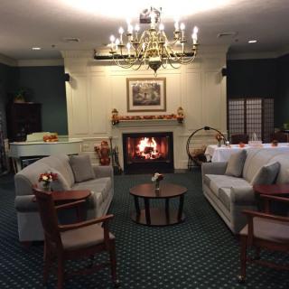 A cozy living room with a fireplace, sofas, and a chandelier.