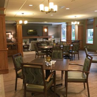 A cozy and inviting dining area with tables set for guests, featuring warm wooden accents and comfortable seating.