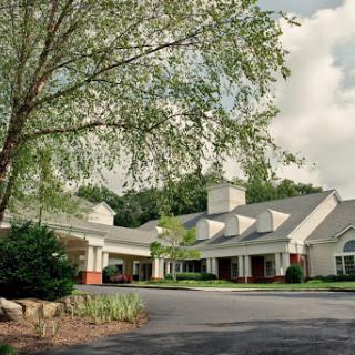 A serene view of a well-designed building surrounded by trees under a cloudy sky.