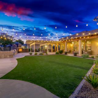 A tranquil outdoor space illuminated by string lights under a beautiful evening sky.