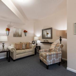 A cozy and elegantly decorated living room featuring a sofa, armchair, and various decor elements.