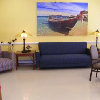 A cozy living room featuring a blue sofa, striped chairs, and a nautical painting on the wall.