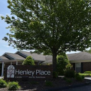 A building with a sign labeled 'Henley Place' surrounded by trees and landscaping.