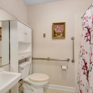 A clean and cozy bathroom with a toilet, sink, mirror, and floral shower curtain.