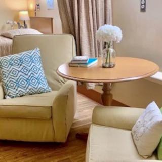 A cozy living room setting with two armchairs, a wooden table, decorative pillows, and flowers.