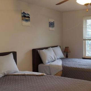 A cozy bedroom with two beds, a window, and decorative wall art.