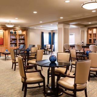 A cozy interior space with tables, chairs, and bookshelves, ideal for reading or relaxing.