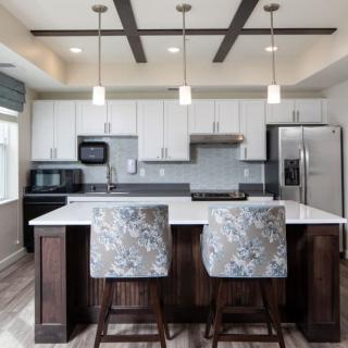 A modern kitchen with white cabinets, stainless steel appliances, and a central island with bar stools.