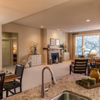 A cozy open-plan living area featuring a fireplace and modern furniture, viewed from the kitchen.