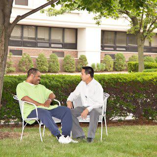 Two people sitting and talking in a garden area.