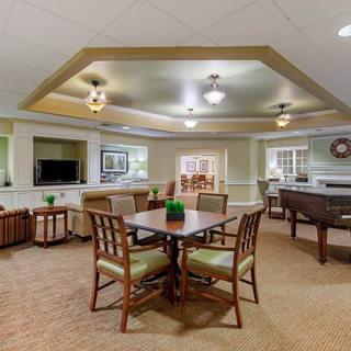 A cozy living room with a central table, comfortable seating, and warm lighting.