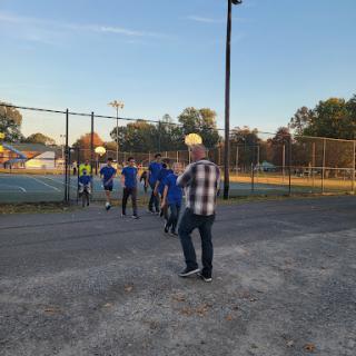 A group of players in blue jerseys walking towards the field as the sun sets.