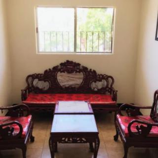 A traditional wooden sofa set with red cushions, accompanied by a matching coffee table, placed in a well-lit living room.