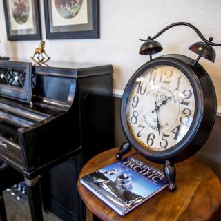 A vintage-style room featuring a large clock and an upright piano.