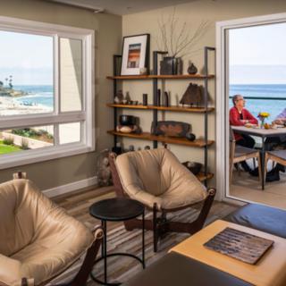 A cozy living room with modern furniture and a beautiful ocean view, leading to a balcony.