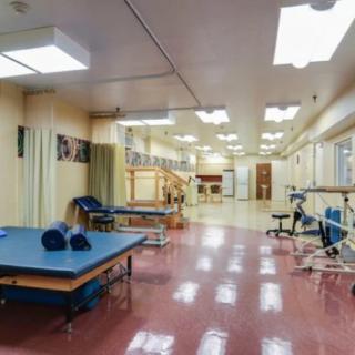 A spacious rehabilitation center equipped with exercise tables and various physical therapy apparatus.