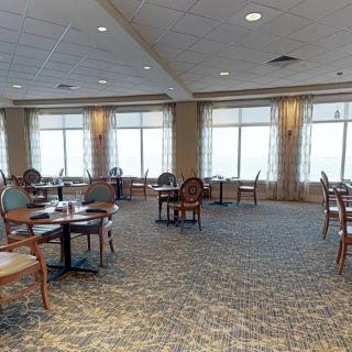 A spacious dining area with large windows and wooden furniture.
