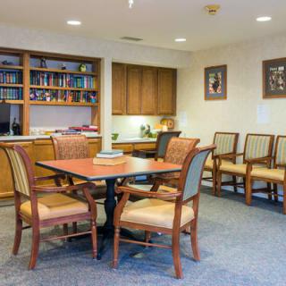 A cozy waiting room with a table and chairs, surrounded by bookshelves and decor.