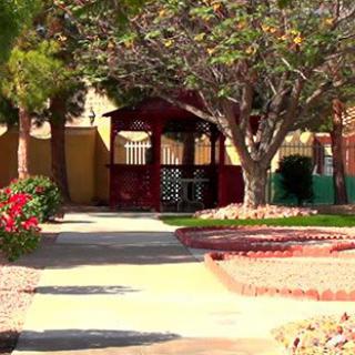 A peaceful garden path leads to a gazebo surrounded by trees.