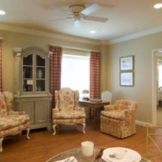 A cozy living room with floral chairs, a cabinet, and patterned curtains.