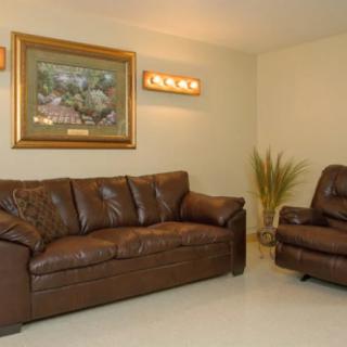 A cozy living room featuring a brown leather sofa set with warm lighting and decorative artwork on the wall.
