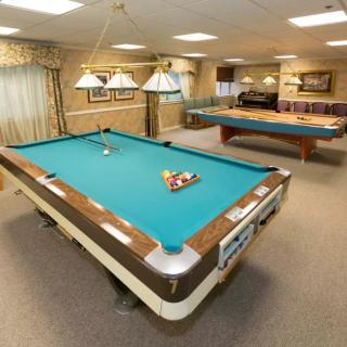 A recreation room featuring multiple pool tables and well-lit playing areas.