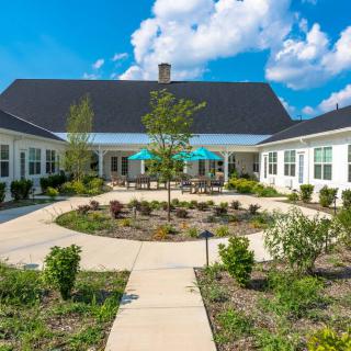 A beautiful residential courtyard with a central garden and surrounding pathways, set under a bright blue sky.
