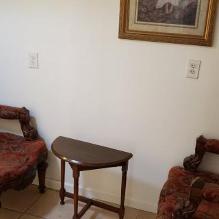 A cozy corner with vintage chairs and a small wooden table, complemented by a framed painting on the wall.
