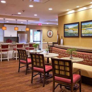 A cozy cafe interior with tables and chairs arranged neatly, featuring artwork on the walls and warm lighting.