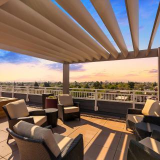 A rooftop lounge area with comfortable seating, offering a scenic view at sunset.